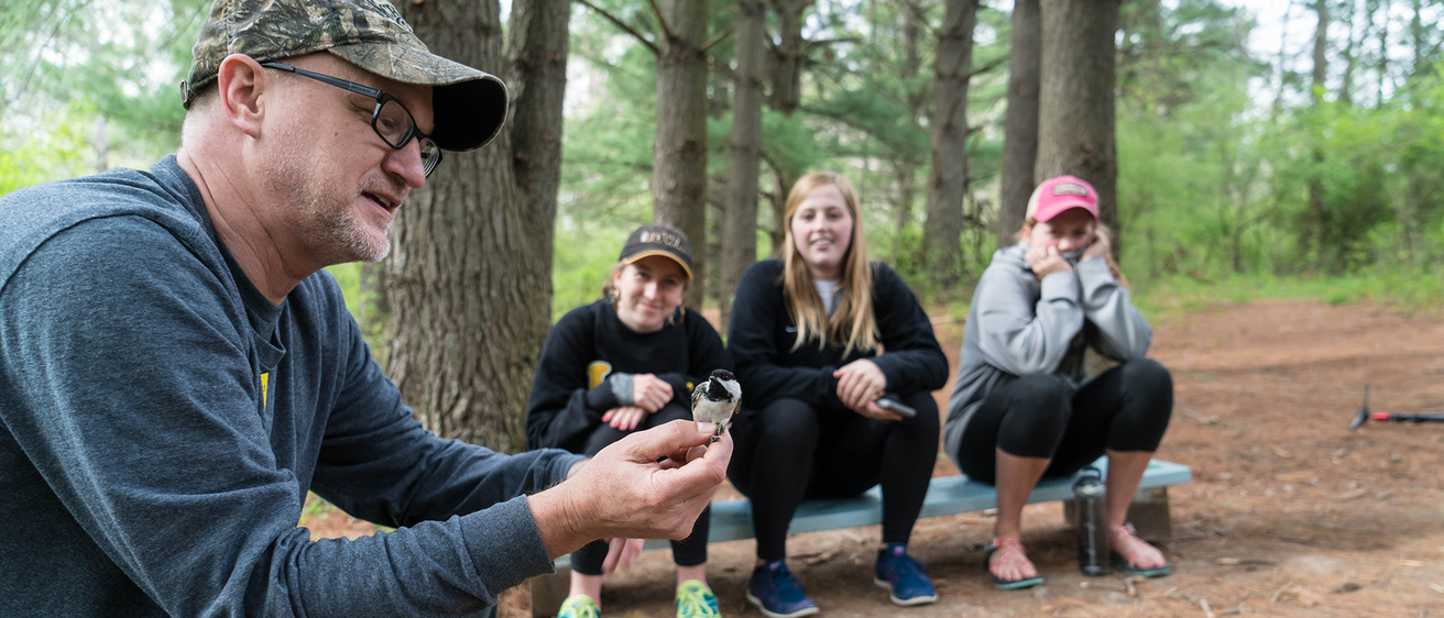 Instructor holds a docile chickadee during banding