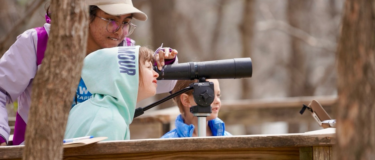 UI WILD volunteer and children looking through telescope
