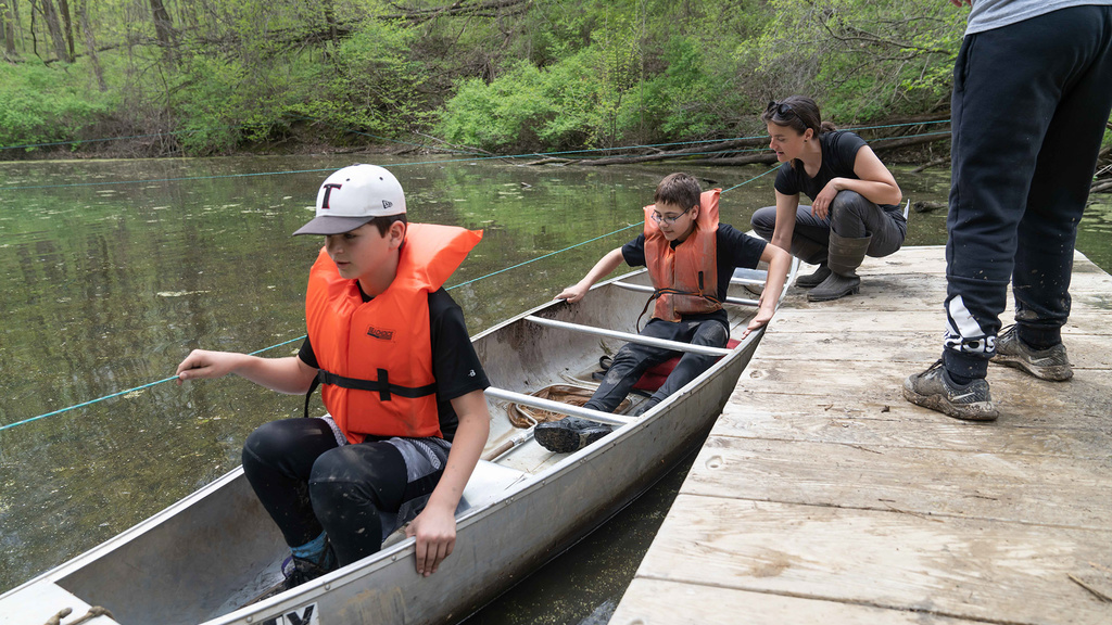 Phoebe Yetley assists students into a canoe in Spider Pond at Macbride Nature Recreation Area.