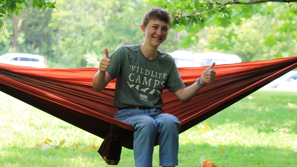 UI Wild camper sitting on a hammock with two thumbs up
