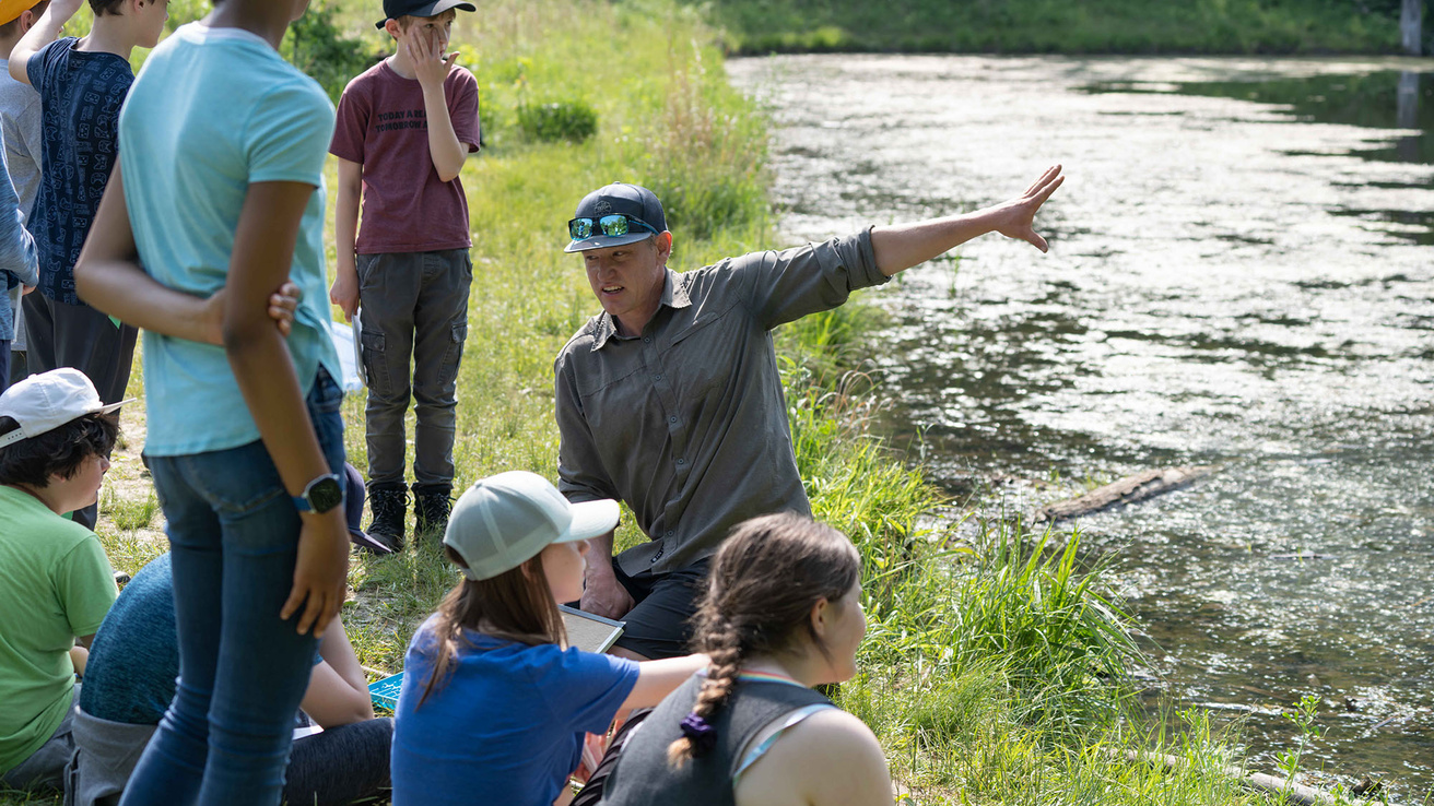 Students along the river listening to an instructor 