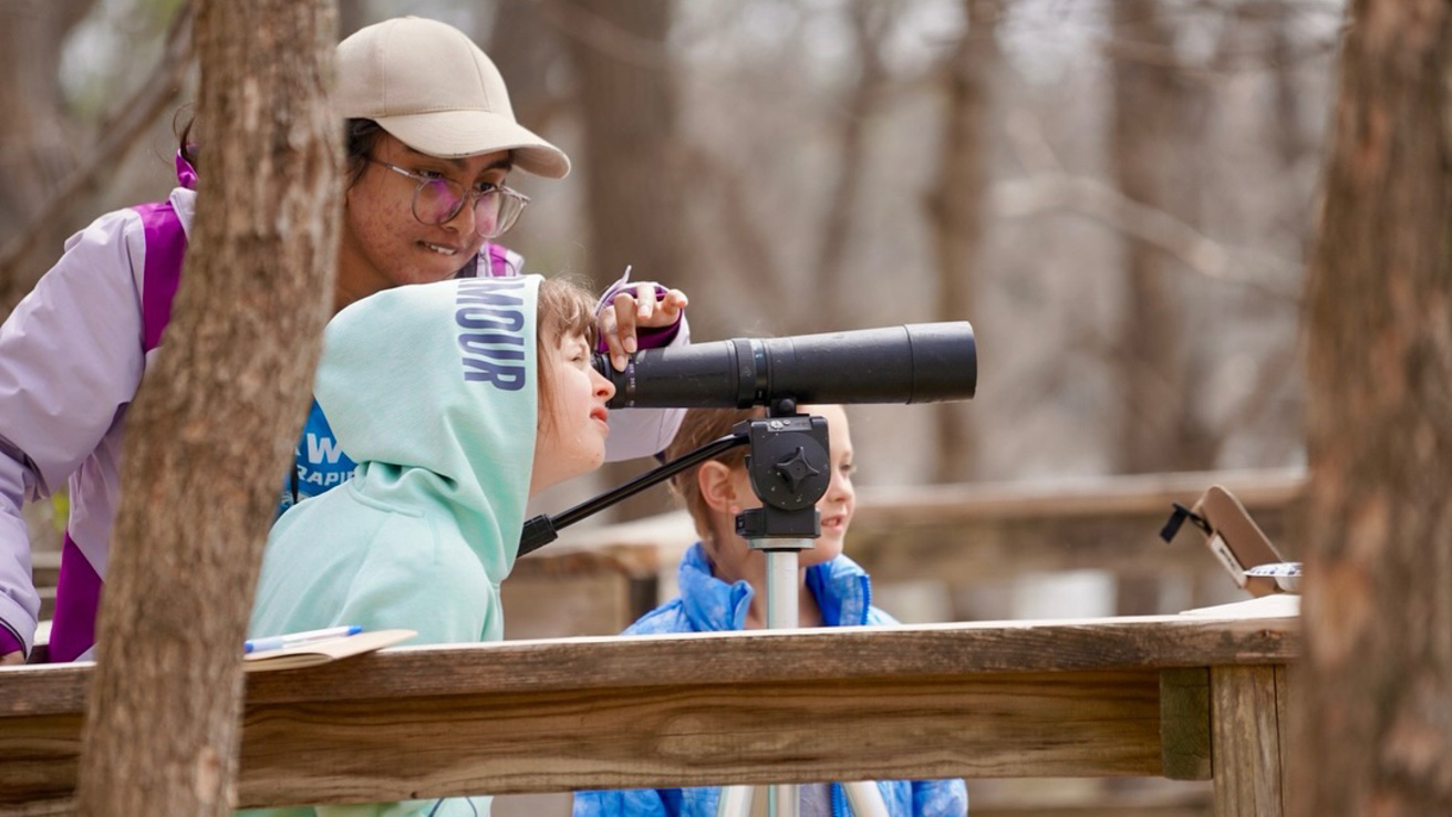 UI WILD volunteer and children looking through telescope